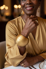 Woman in a gold dress with statement lightweight jewelry bangle handmade from recycled bamboo