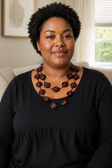A woman with short curly black hair wearing a black long-sleeve top and a chunky wooden disks LOVE & HOPE necklace by Jianhui London.