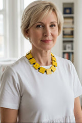 Woman wearing a white top and yellow Sustainable necklace handmade from recycled wood. The necklace is perfect gift for your mom