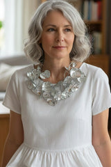Woman wearing a white dress with a Statement lightweight necklace handmade from recycled plastic water bottles in a room with a bookshelf.